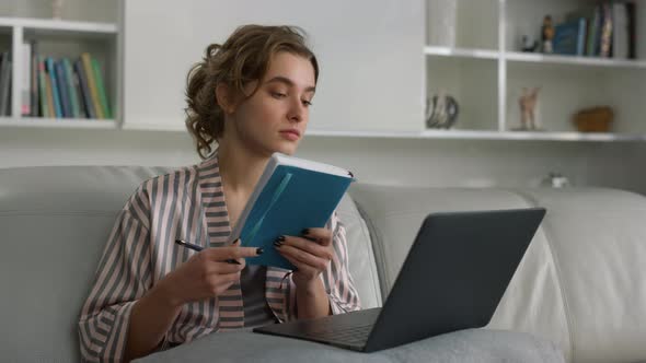 Closeup Young Businesswoman Making Notes Watching Online Conference at Home