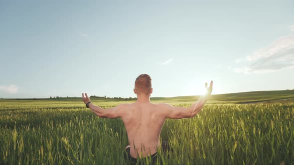A Happy Man Without a Tshirt is Sitting in the Middle of a Field