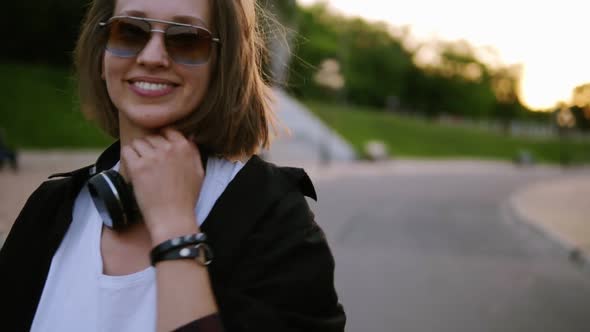 Attractive Young Woman in a Stylish Outfit Turns to Camera and Smiles Seductively Continues Walking