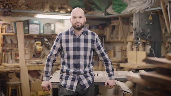 A Brutal and Bald Man in a Carpentry Workshop