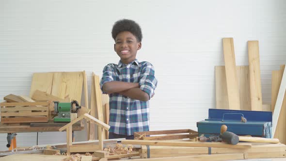 Smiling African-American boy carpenter standing with his arms crossed showing confidence 