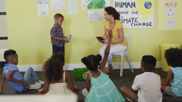 Video of happy caucasian female teacher and class of diverse pupils studying ecology in classroom