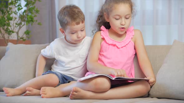 Cute Children,sister with a Younger Brother, Looking at a Book Magazine Textbook Dictionary Tablet