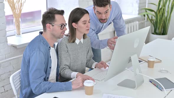 Attractive Team of Creative Professionals Working on Desktop Together