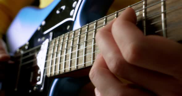 Male Guitarist Playing Fingerpicking with a Plectrum on a Blue Electric Guitar