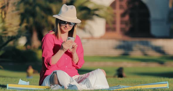 Relaxed Young Attractive Woman Using Smart Phone Surfing Social Media in Park
