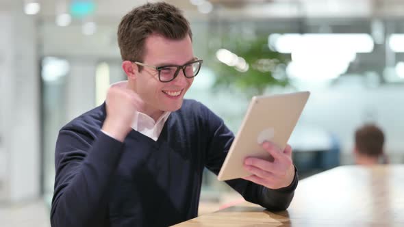 Young Businessman Celebrating Success on Tablet 