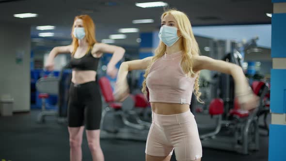 Fit Slim Caucasian Women Training Hand Muscles Exercising in Gym Wearing Coronavirus Face Masks