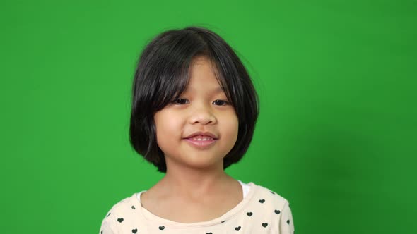 Portrait of happy, smiling, and funny Asian child girl on green screen background, a child looking a