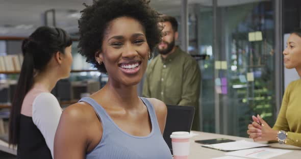 Portrait of happy african american businesswoman over diverse business colleagues discussing