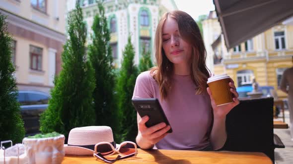 Young Woman Talking on the Phone in a Cafe on a Summer Terrace