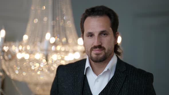 Portrait of an Unshaven Man in a White Shirt and Suit Against the Background of a Blurred Crystal