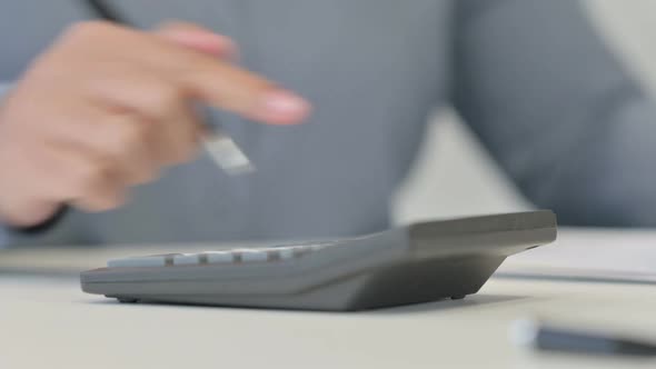 Close Up of African Woman Using Calculator Writing on Paper