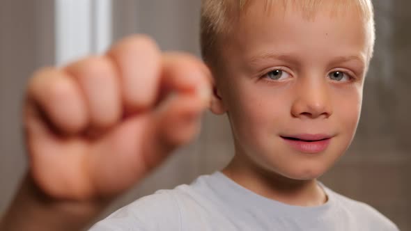 Closeup of a Little Boy Holding His Fallen Baby Tooth in His Hands