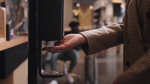 Close Up Washing Hands with an Automatic Alcohol Sanitizer Dispenser at Hotel