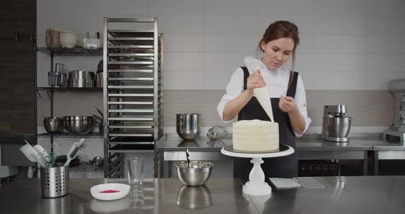 Using a Pastry Sleeve the Pastry Chef Applies Cream to the Cake