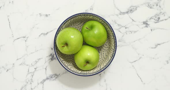 Green Apples in Bowl on White Marble Table, Top View.