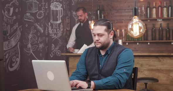 Man with Long Hair and Beard Works Remotely and Is Getting a Fresh Coffee