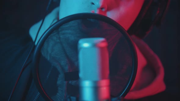 A Man in Hoodie Rapping in the Studio and Recording His Track