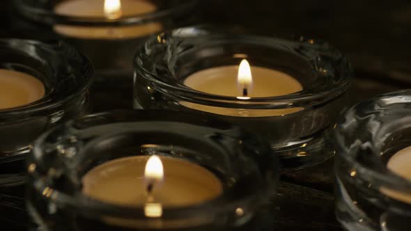 Tea candles with flaming wicks on a wooden background 