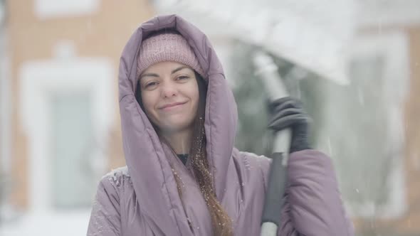 Satisfied Young Caucasian Woman Putting Shovel on Shoulder and Smiling with Toothy Smile Looking at