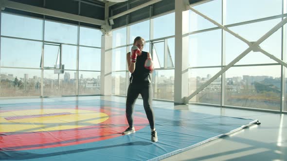 Confident Woman Boxer Training in Gym Alone Practicing Punches Moving Hands Wearing Gloves