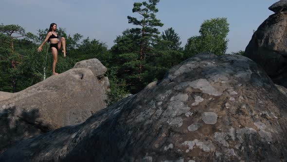 Pretty Woman Balancing on One Leg Climbs Cliff