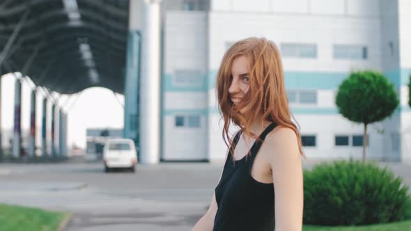 Beautiful Smiling Redhaired Woman Walks on Street at Sunset