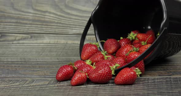 Strawberries in a Small Black Bucket on the Wooden Table