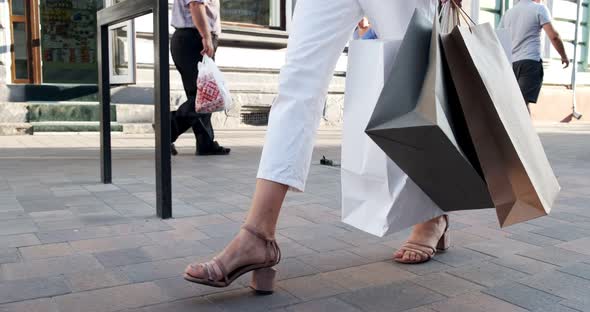 Bottom View of Shopping Bags in Hands. Beautiful, Young Woman Walks Through the City Shopping with