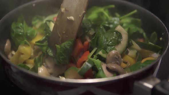 Homemade stir fry. A colorful pan full of vegetables and mushrooms. Slow motion stirring. Bright Gre