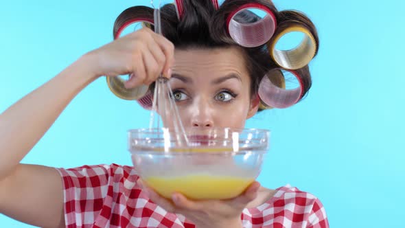 Woman Whisking Eggs and Curling Hair