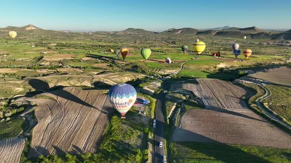 Hot air balloons fly over the mountainous landscape of Cappadocia, Turkey.