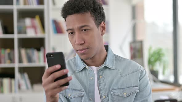 Young African American Man Using Smartphone, Browsing Internet 