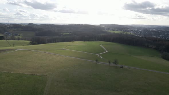 Lush green fields in North Rhine Westfalia on a cloudy winter day. Aerial panning orbit shot