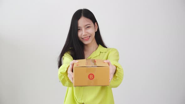 Young asian woman smiling and holding cardboard box at home, happy female carrying parcel box giving