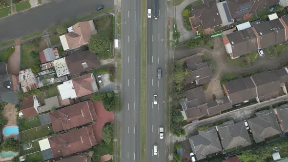 4K aerial dual carriageway or divided highway among the neighborhood homes, houses and properties wi