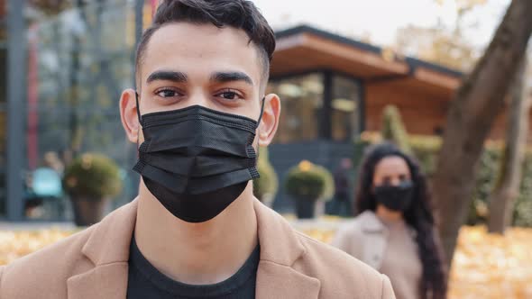 Attractive Brunet Oriental Man in Black Medical Mask Attentively Looking at Camera Standing in