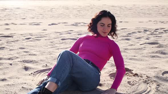 Young Woman Playing with Sand on the Beach