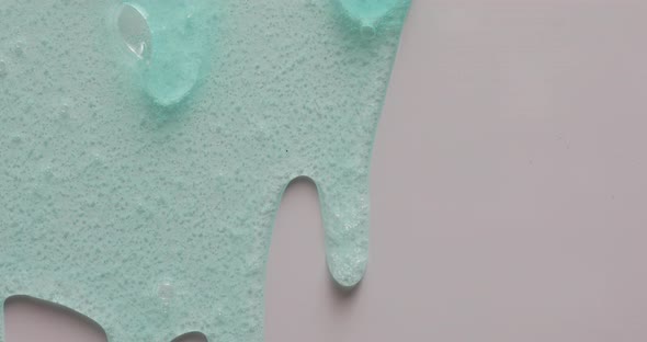Blue cream liquid gel serum flowing down on grey texture