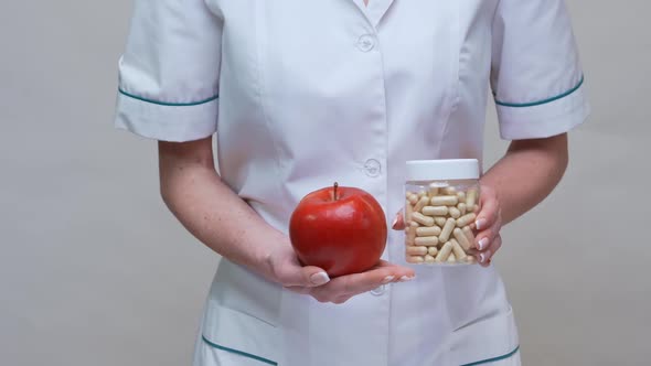 Nutritionist Doctor Healthy Lifestyle Concept - Holding Organic Red Apple and Jar of Vitamin Pills