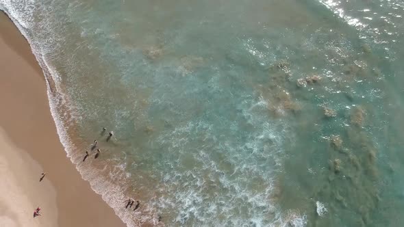 360 Aerial shot of waves hitting shore and people bathing