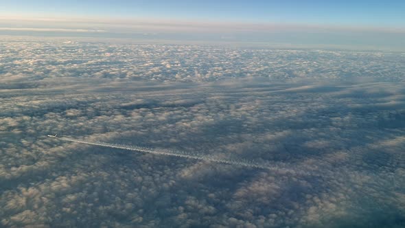 Incredible view from the cockpit of an airplane flying high above the clouds leaving a long white co