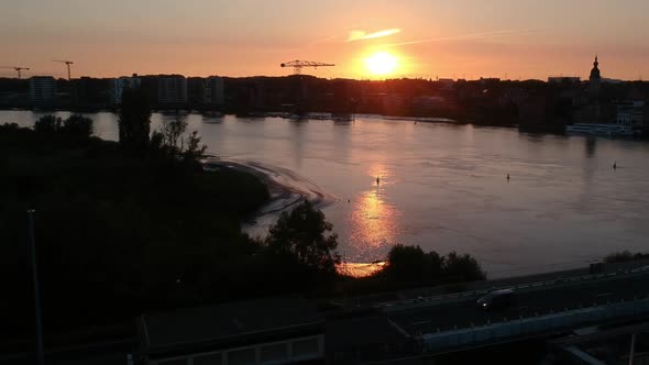 Majestic sunset over city silhouette while cars drive over bridge, aerial drone view