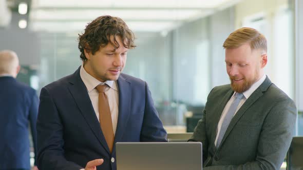 Colleagues Using Laptop and Talking in Office