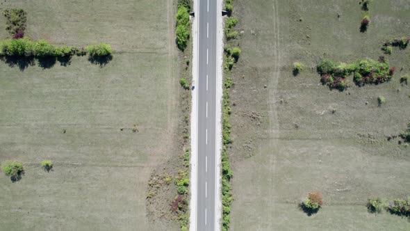 Top Aerial View of an Empty Asphalt Road on the Plateau Between Green Fields