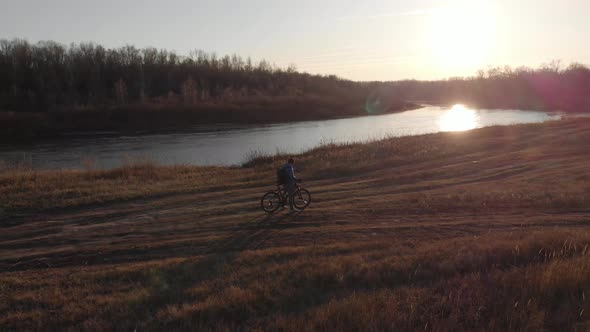 Aerial View of a Cyclist Riding on His Bicycle in Mountain at Sunset.