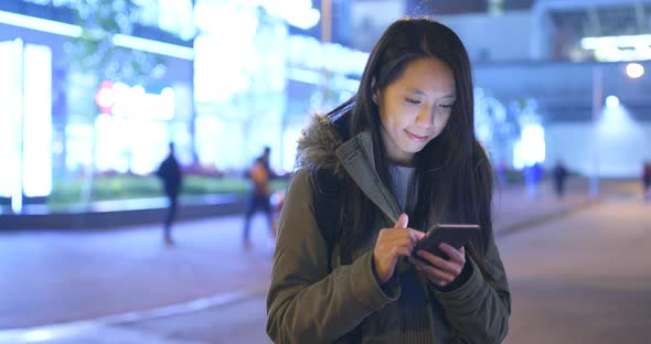 Asian woman use of mobile phone in city at night