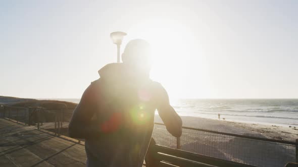 Focused african american man boxing and running, exercising outdoors by the sea