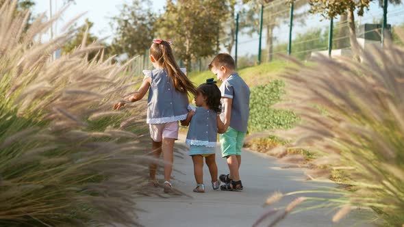 Happy children siblings dressed similar walking and playing in the park